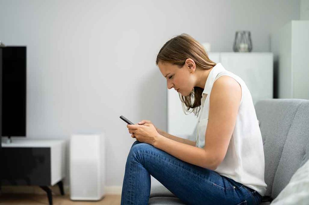 mujer agachada viendo celular