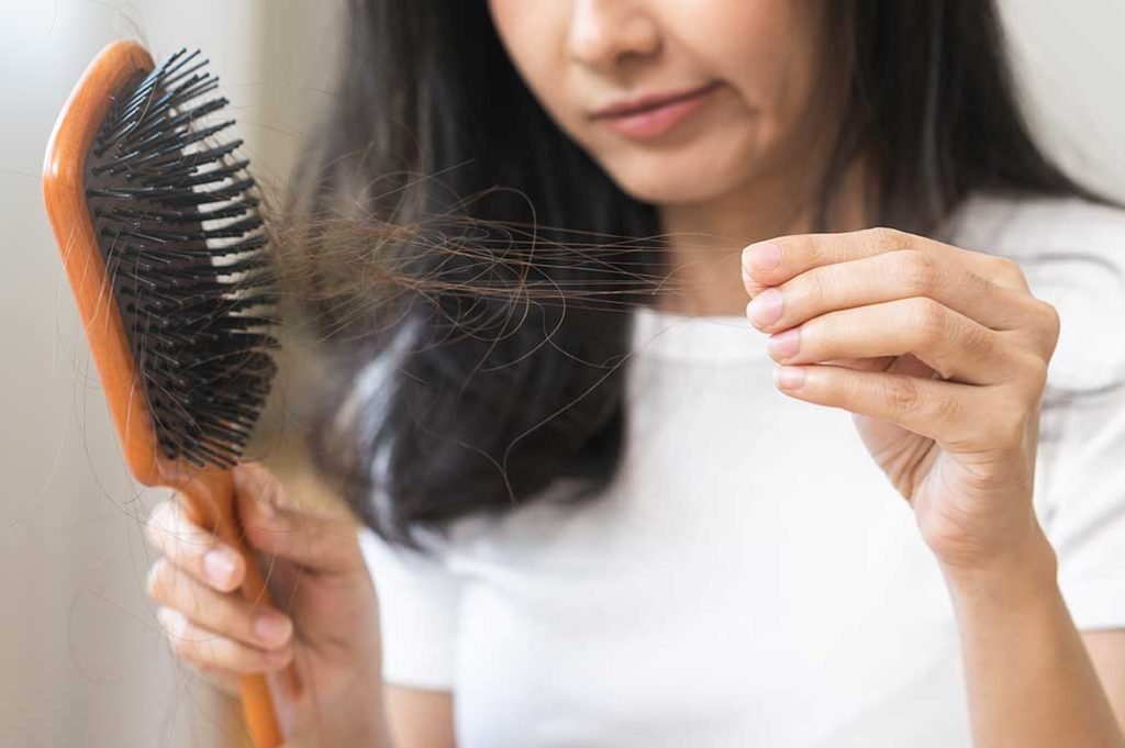 mujer sacando el pelo del cepillo